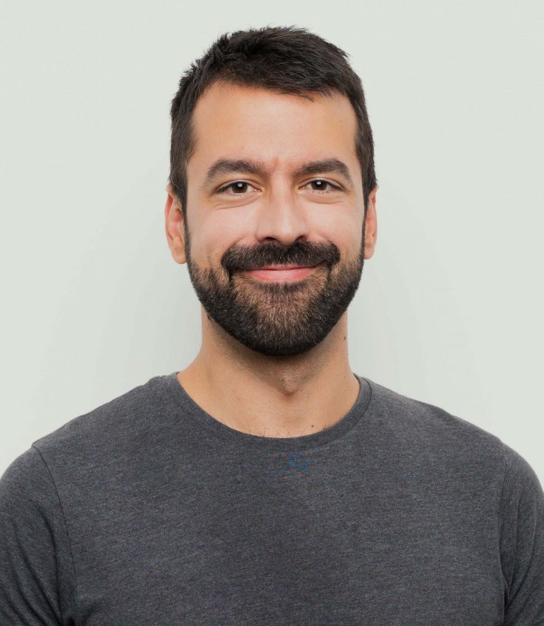 Man with mustache and trimmed beard smiles, happy with his Invisalign NYC