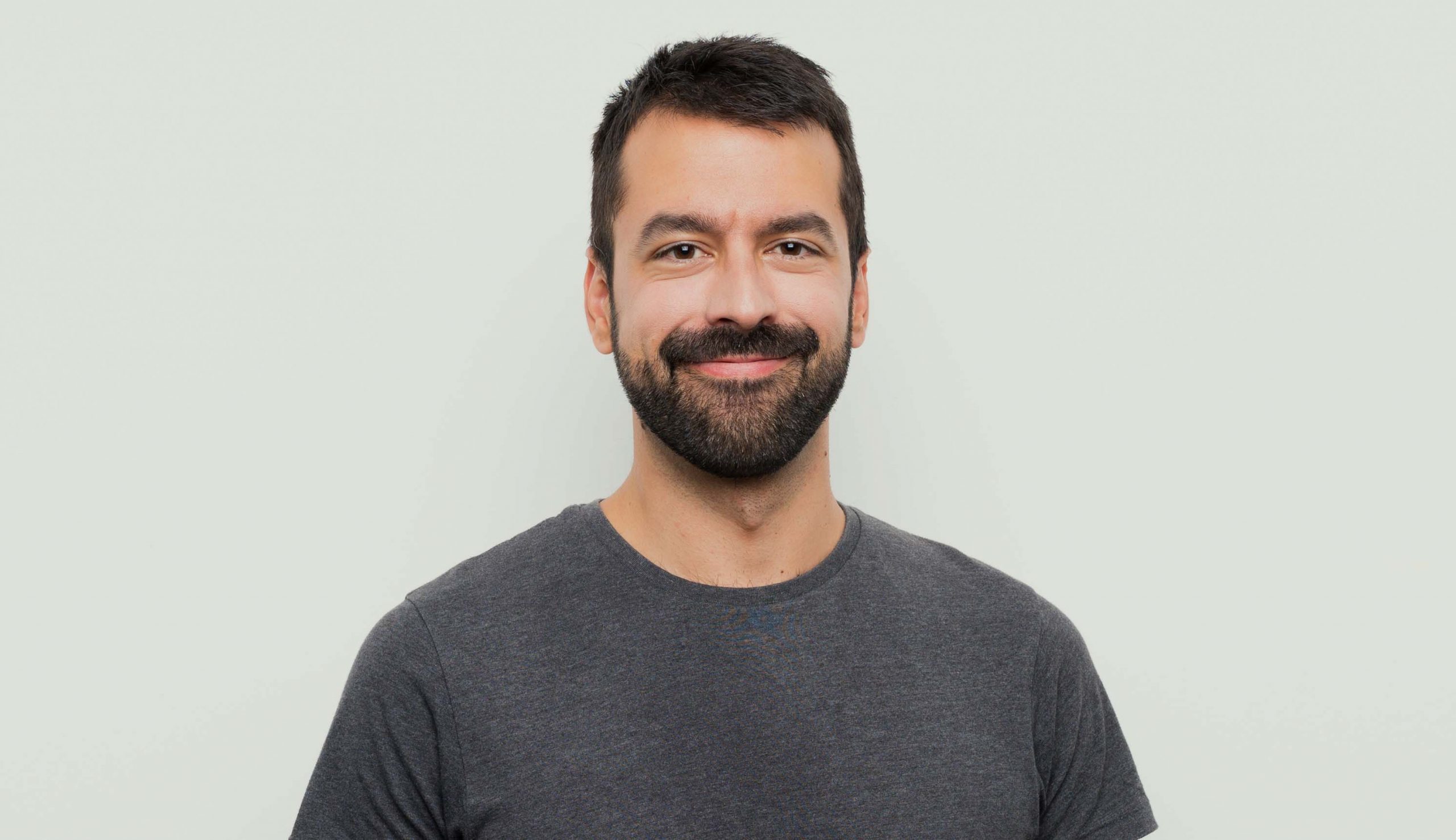 Man with mustache and trimmed beard smiles, happy with his Invisalign NYC